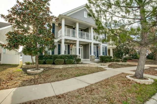 a front view of a house with garden and tree