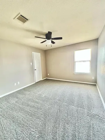 an empty room with a ceiling fan and window