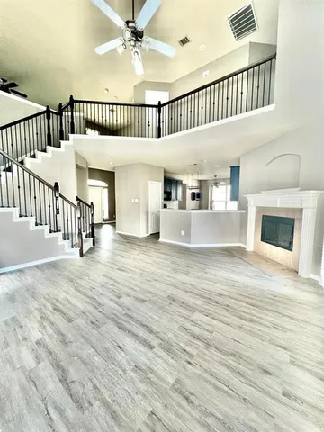 an empty room with wooden floor windows and a ceiling fan