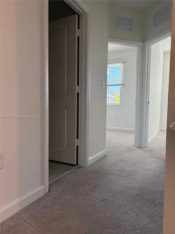 a view of an empty room with closet and a bathroom