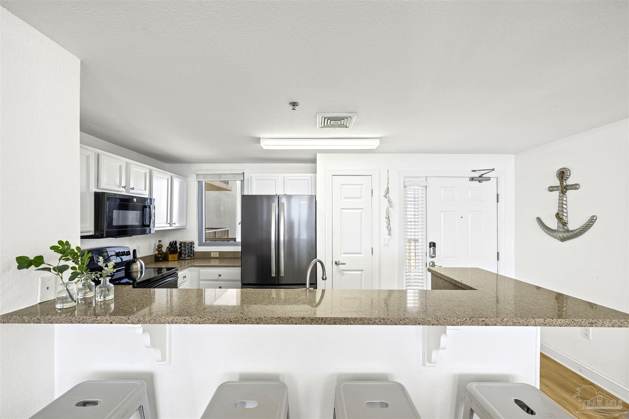 850 Fort Pickens Road, Unit 1040 Pensacola Beach, FL 32561 - Photo 10 of 37 a kitchen with granite countertop a refrigerator and a sink