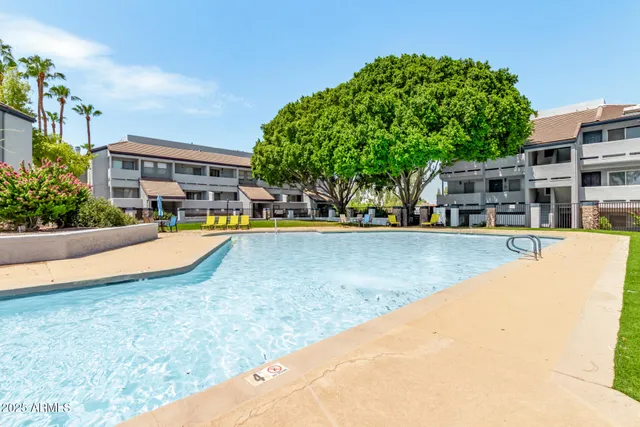 a view of swimming pool with outdoor seating and house in the background