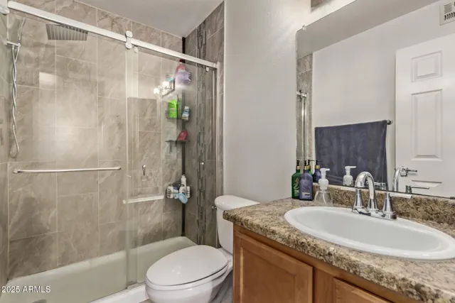 a bathroom with a granite countertop sink toilet and shower