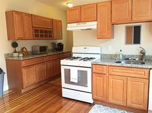 12 Union Street Beverly, MA 01915 - Photo 3 of 19 a kitchen with stainless steel appliances granite countertop a stove a sink dishwasher and a microwave oven with cabinets