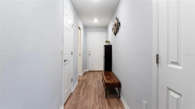 a view of a hallway with wooden floor and a bathroom