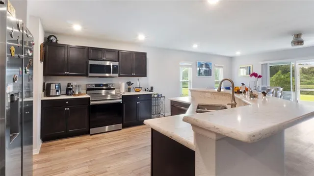 a kitchen with stainless steel appliances kitchen island granite countertop a refrigerator and a stove top oven