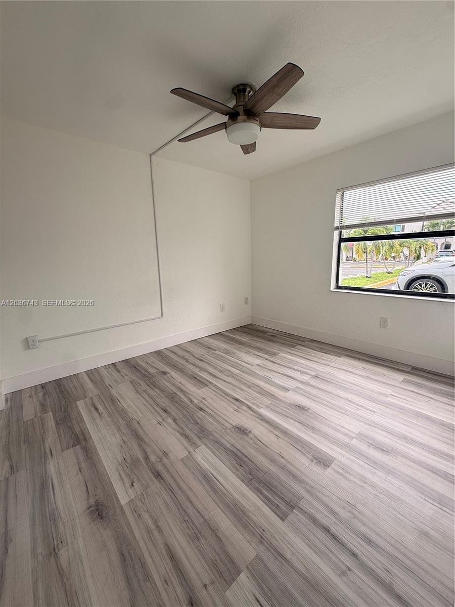 10875 Northwest 7th Street, Unit 1136 Miami, FL 33172 - Photo 14 of 25 a view of empty room with wooden floor and fan