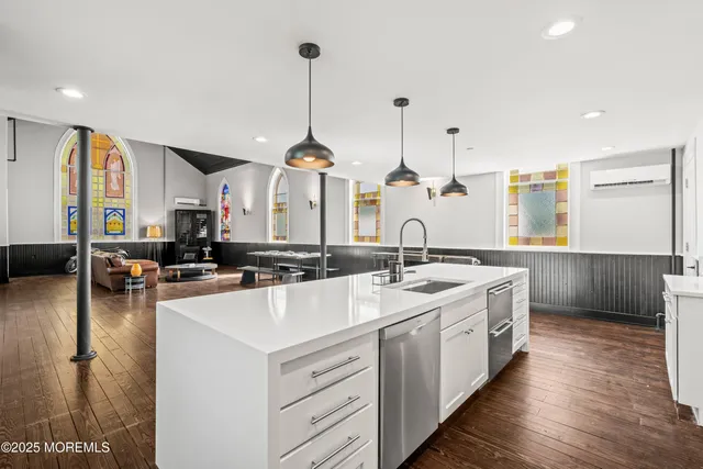 a view of a kitchen with kitchen island a large counter top space a sink stainless steel appliances and cabinets