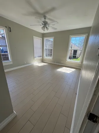 an empty room with chandelier fan and windows