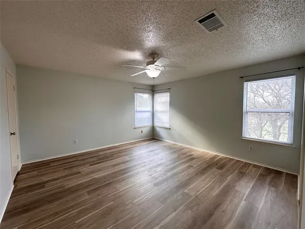 an empty room with wooden floor and windows