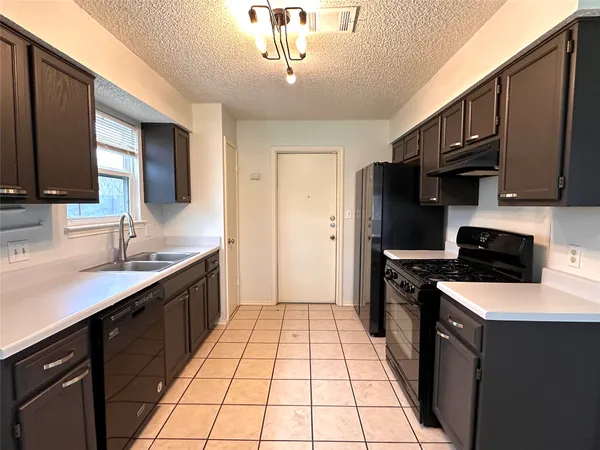 a kitchen with a sink a stove top oven a refrigerator cabinets and a window