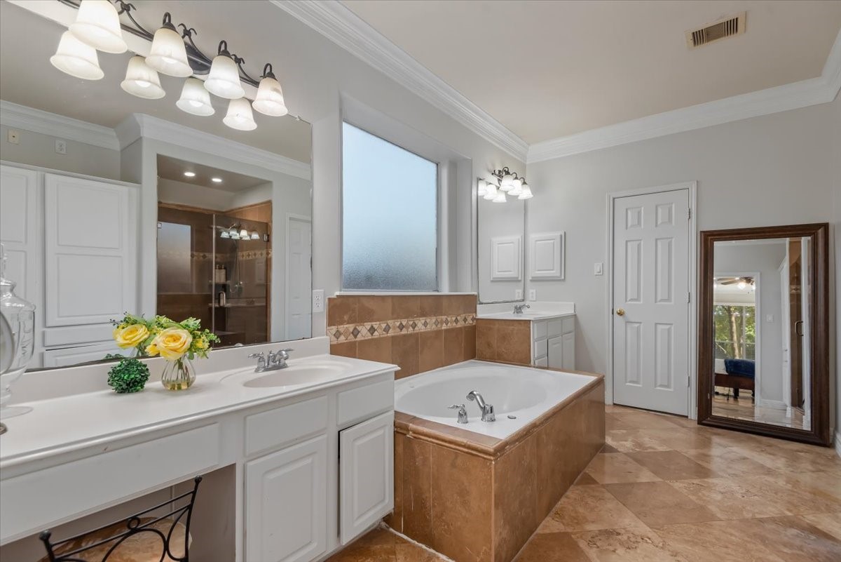 6507 Quiet Pointe Drive Spring, TX 77389 - Photo 15 of 45 This elegant bathroom features a spacious layout with a large soaking tub, dual vanities, and a separate glass-enclosed shower. The room is well-lit with stylish fixtures, and the neutral tile flooring adds a touch of sophistication. A full-length mirror and decorative crown molding complete the space.