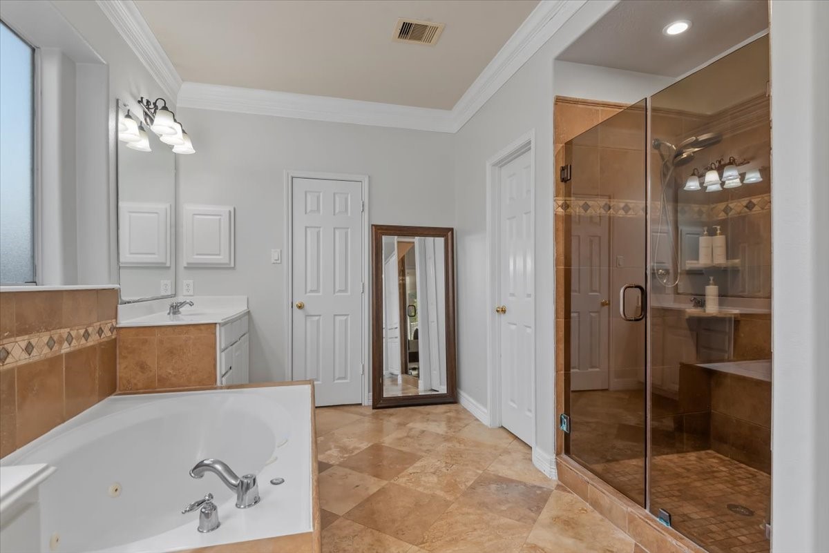 6507 Quiet Pointe Drive Spring, TX 77389 - Photo 16 of 45 This bathroom features a luxurious soaking tub and a spacious glass-enclosed shower. It has elegant tile flooring, dual vanity sinks, and ample natural light, creating a bright and inviting atmosphere.