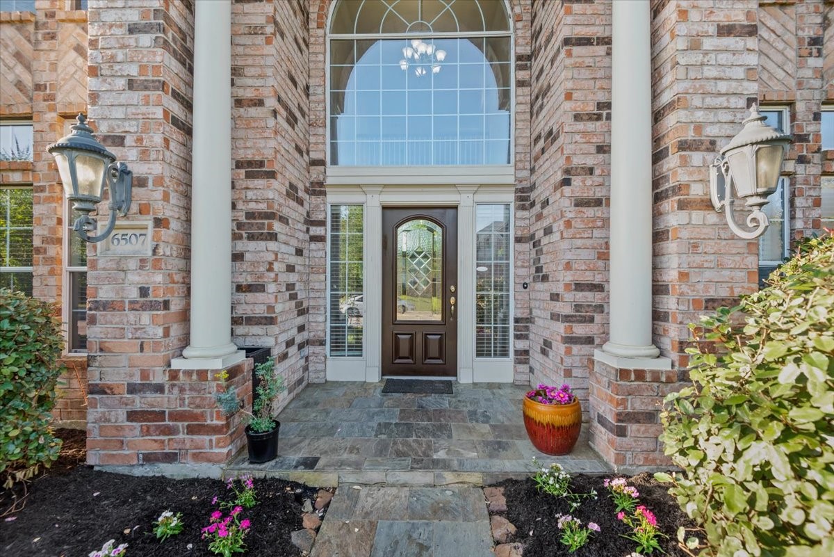 6507 Quiet Pointe Drive Spring, TX 77389 - Photo 2 of 45 Elegant brick entryway with large arched window, decorative front door, and charming landscaping. Flanked by classic lantern-style lights and impressive columns, offering a welcoming and prestigious entrance.