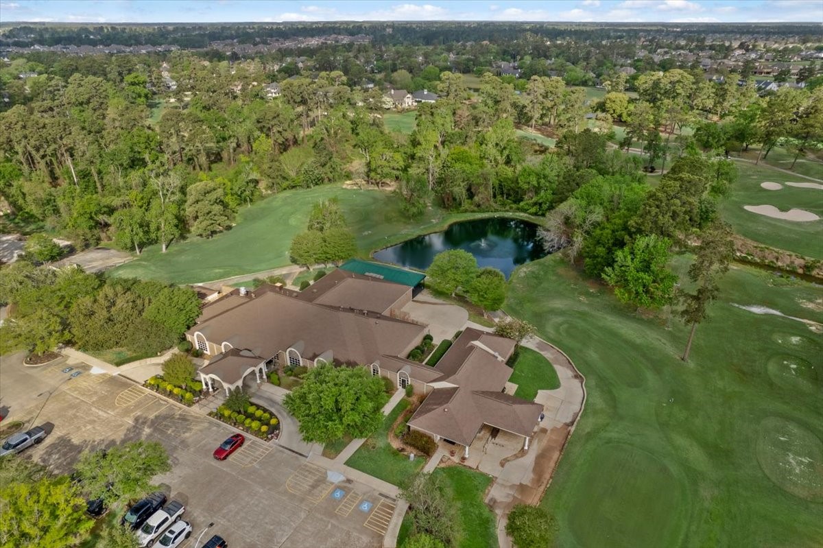 6507 Quiet Pointe Drive Spring, TX 77389 - Photo 41 of 45 This aerial photo showcases a spacious property surrounded by lush greenery and a golf course. It features a large building with ample parking, set amidst a serene landscape with a small pond and mature trees, offering a tranquil and scenic environment.