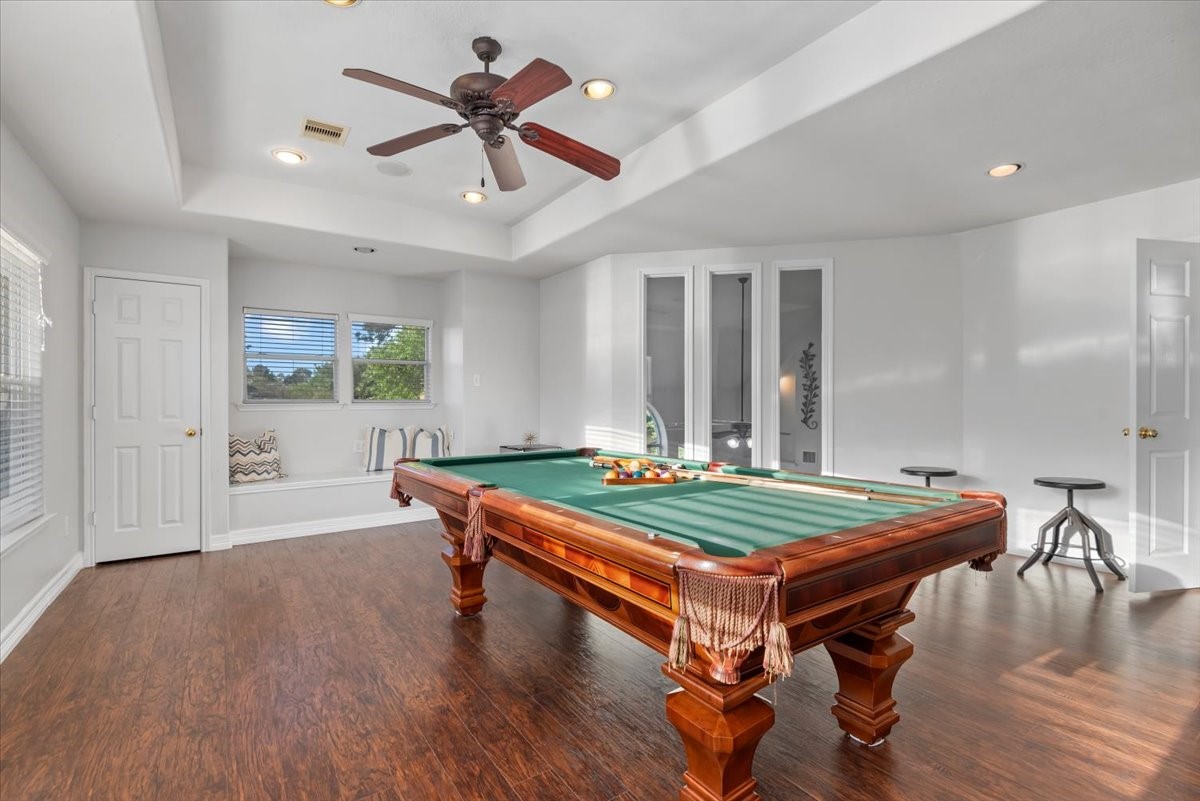 6507 Quiet Pointe Drive Spring, TX 77389 - Photo 5 of 45 Bright and spacious game room with hardwood floors, featuring a classic pool table under recessed lighting. The room includes a ceiling fan, window seating area, and modern accents, perfect for entertaining.