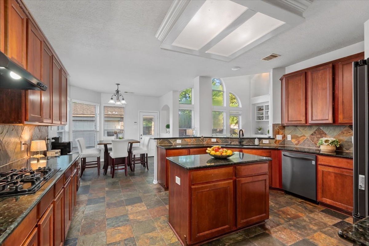 6507 Quiet Pointe Drive Spring, TX 77389 - Photo 10 of 45 Enormous bright and inviting kitchen with an open-concept layout, granite countertops, and a spacious center island perfect for entertaining. . Abundant natural light pours in through large windows, seamlessly connecting the kitchen to the dining area. Complete with stainless steel appliances, ample counter space, and a functional layout, this kitchen is ideal for both everyday living and hosting guests.