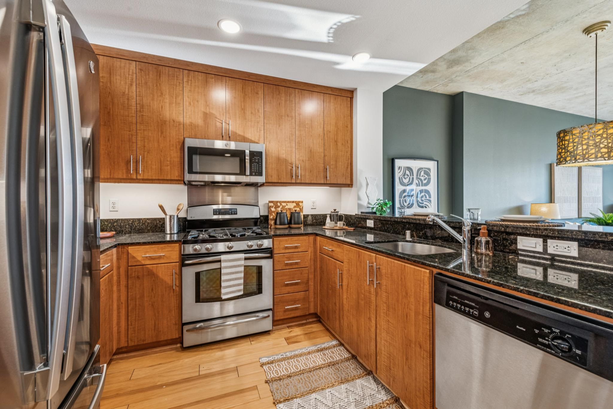 288 3rd Street, Unit 406 Oakland, CA 94607 - Photo 12 of 32 a kitchen with stainless steel appliances granite countertop a stove a sink and a microwave