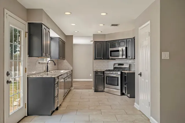 a large kitchen with stainless steel appliances granite countertop a stove and a sink
