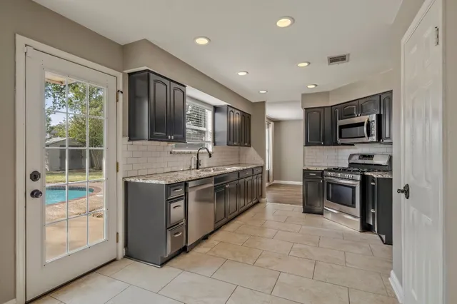 a large kitchen with stainless steel appliances granite countertop a stove and a sink