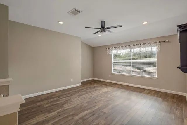 a view of an empty room with wooden floor and a window