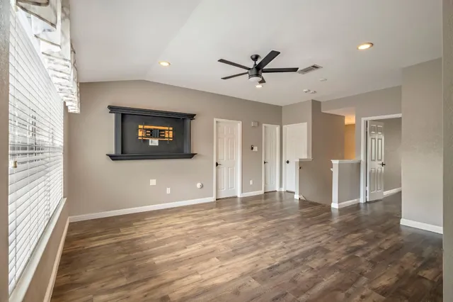 a view of a big room with wooden floor and windows