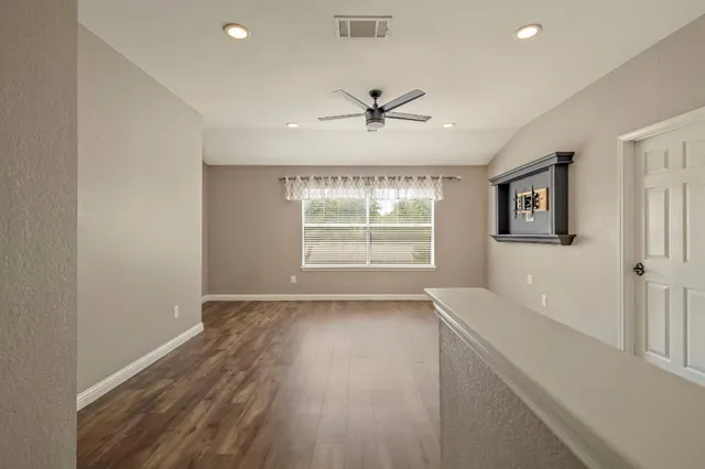 a view of an empty room with a window and wooden floor