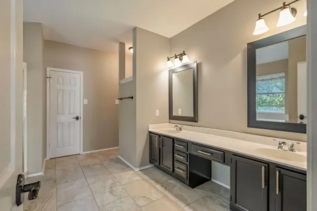 a spacious bathroom with a double vanity sink a mirror and a bathtub