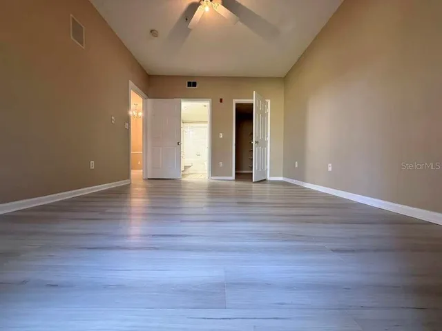a view of an empty room with window and wooden floor