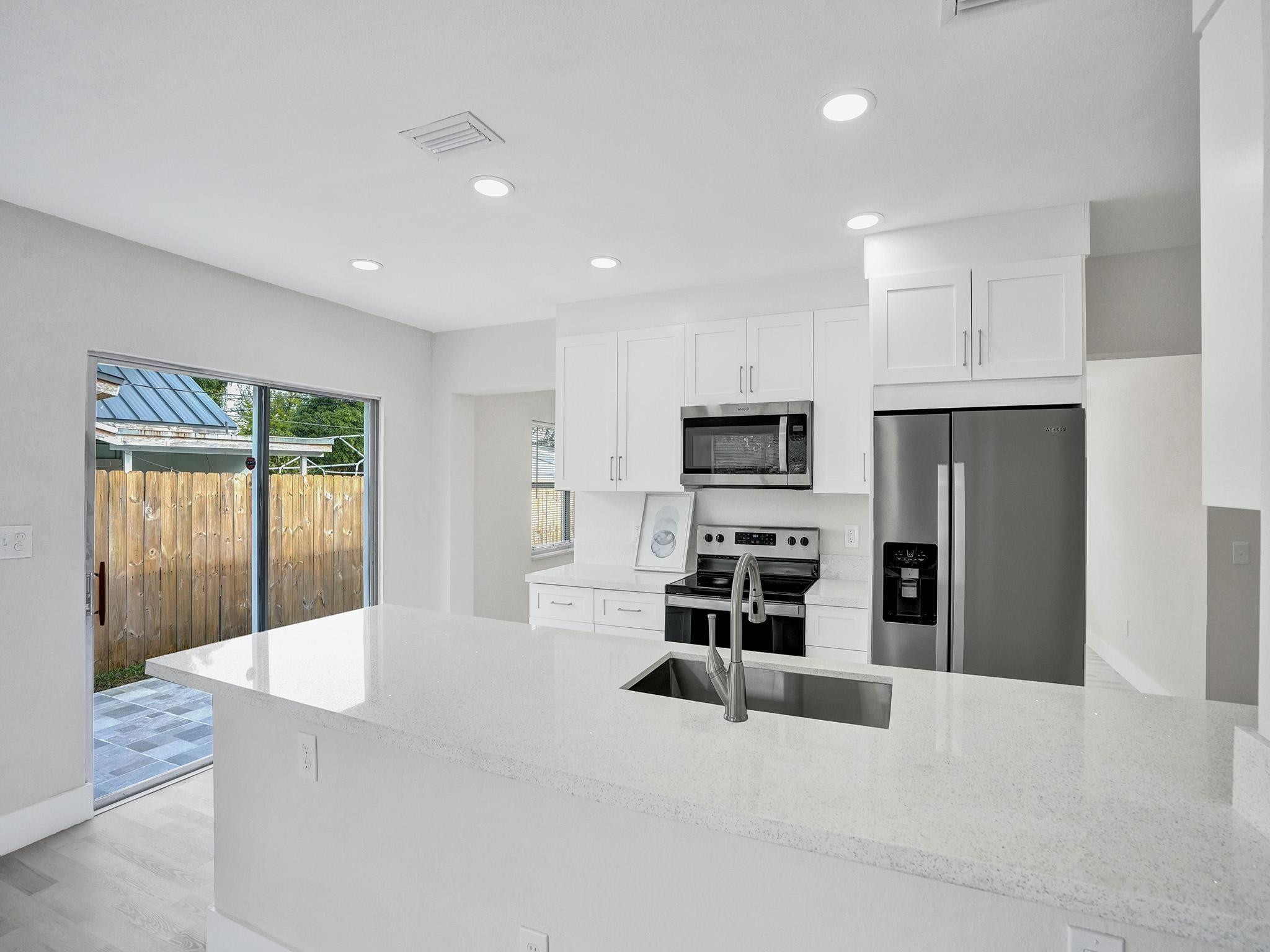 631 North 69th Terrace Hollywood, FL 33024 - Photo 37 of 60 a large kitchen with stainless steel appliances kitchen island granite countertop a refrigerator and a stove top oven