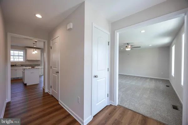 a view of a hallway with wooden floor a bathroom and a sink