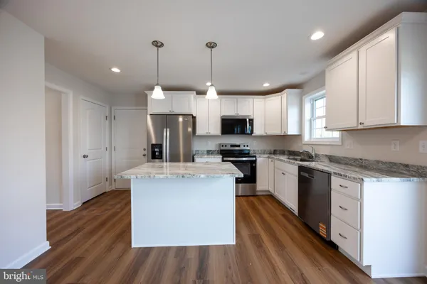 a kitchen with kitchen island stainless steel appliances a sink cabinets and wooden floor