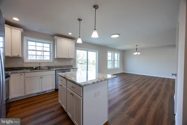 a kitchen with stainless steel appliances granite countertop wooden cabinets a center island and a window