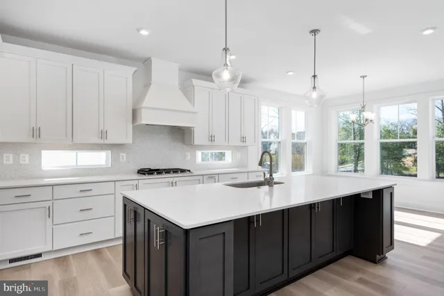 a kitchen with a stove center island a sink cabinets and wooden floor