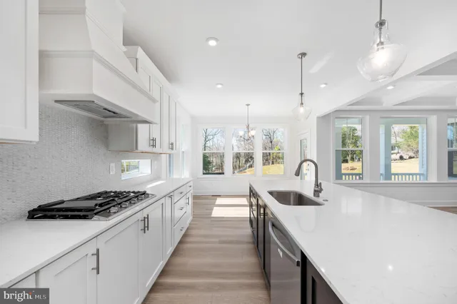 a large white kitchen with kitchen island a sink stainless steel appliances and cabinets