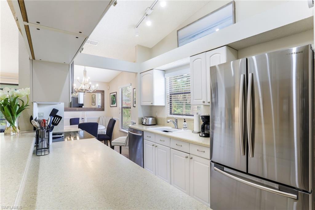 633 91st Avenue North Naples, FL 34108 - Photo 13 of 25 a kitchen with stainless steel appliances a refrigerator a sink a stove and white cabinets