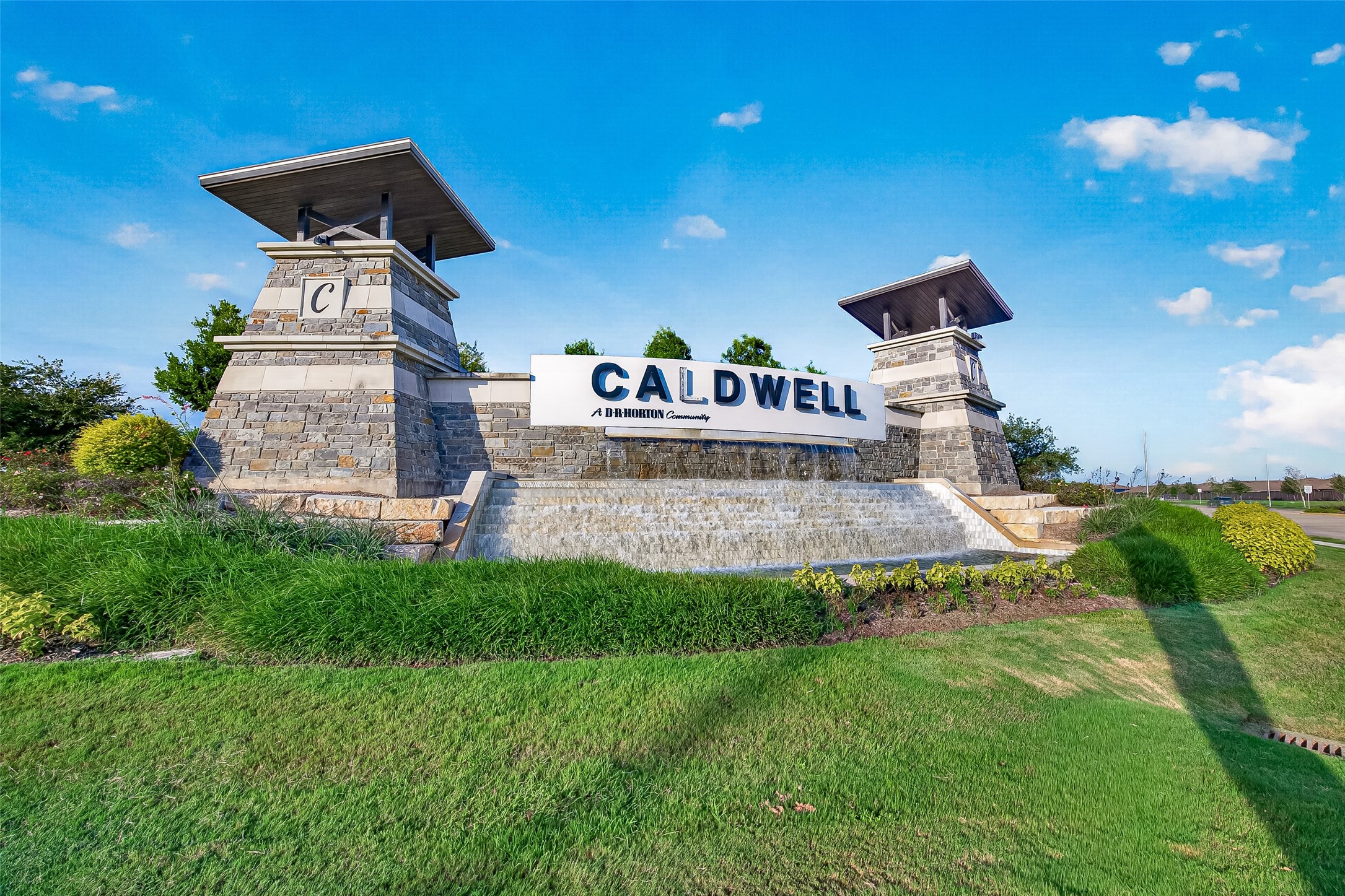 7923 Sleek Flock Lane Rosharon, TX 77583 - Photo 27 of 29 Stunning entrance to the Caldwell community, featuring elegant stonework and a cascading water feature, surrounded by lush greenery.