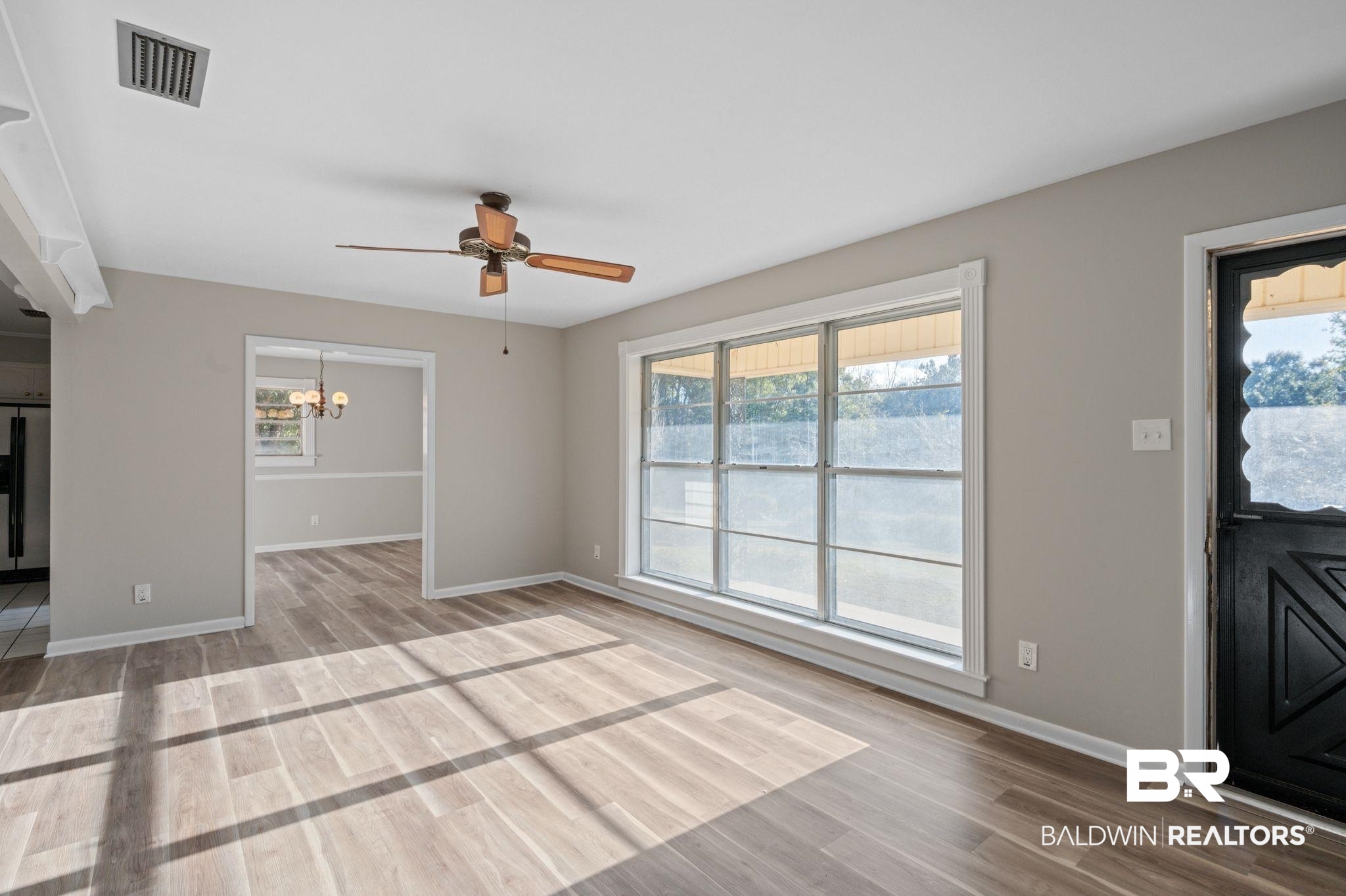 909 Caroline Avenue Daphne, AL 36526 - Photo 6 of 46 Unfurnished living room featuring wood-type flooring and ceiling fan with notable chandelier