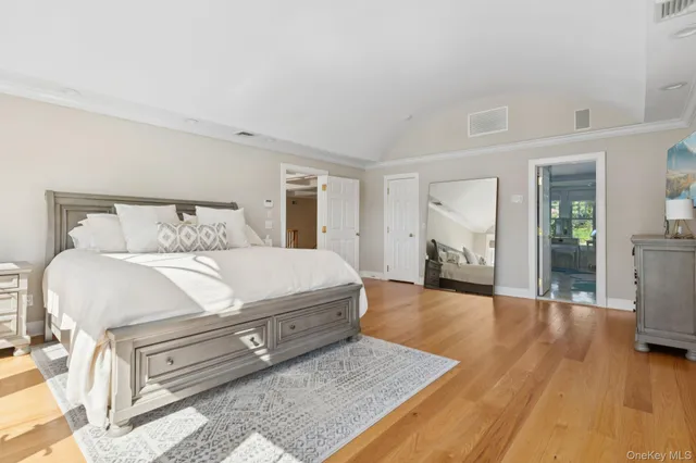 a spacious bedroom with a bed and wooden floor