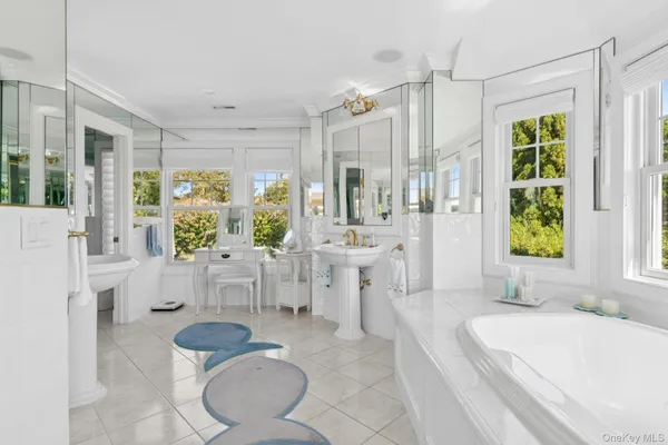 a spacious bathroom with a tub sink and mirror