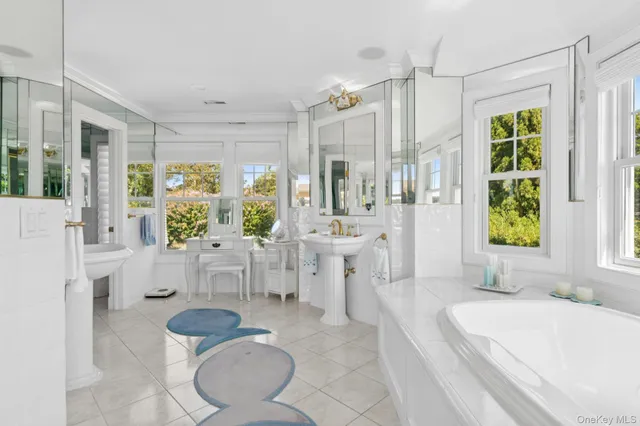 a spacious bathroom with a tub sink and mirror