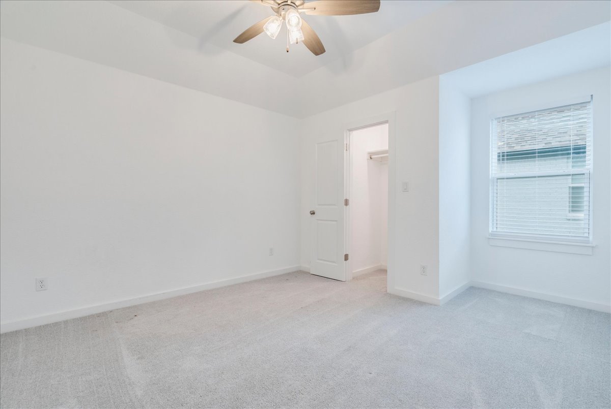 8008 Prairie Rye Drive Lago Vista, TX 78645 - Photo 16 of 40 Bright room featuring light gray carpet, white walls, and a tray ceiling with a ceiling fan