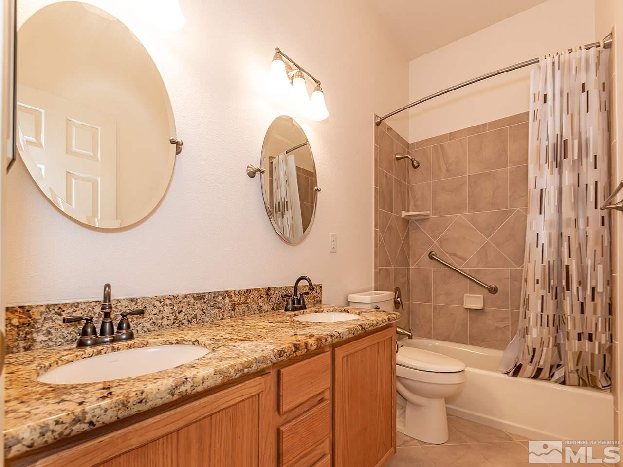10440 Silver Rush Court Reno, NV 89521 - Photo 18 of 22 a bathroom with a granite countertop sink a toilet and a mirror