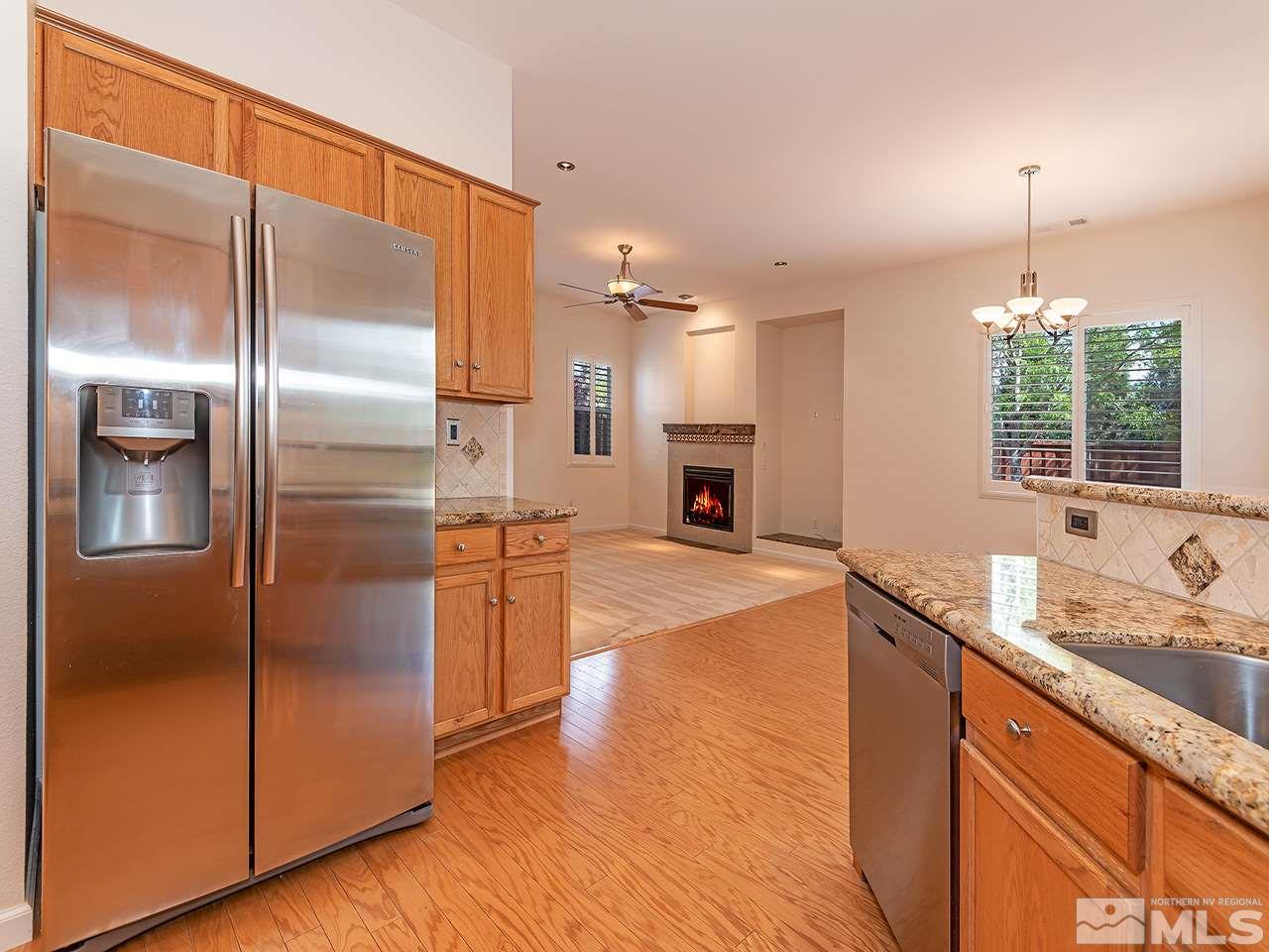 10440 Silver Rush Court Reno, NV 89521 - Photo 9 of 22 a kitchen with kitchen island granite countertop a refrigerator a sink and a wooden floor