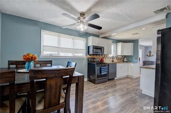 a kitchen with stainless steel appliances granite countertop a refrigerator a sink dishwasher a dining table and chairs with wooden floor