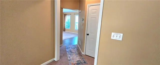 a view of a hallway with wooden floor and a bathroom