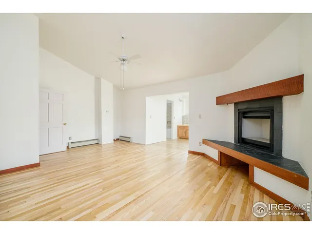 a view of empty room with wooden floor and fireplace