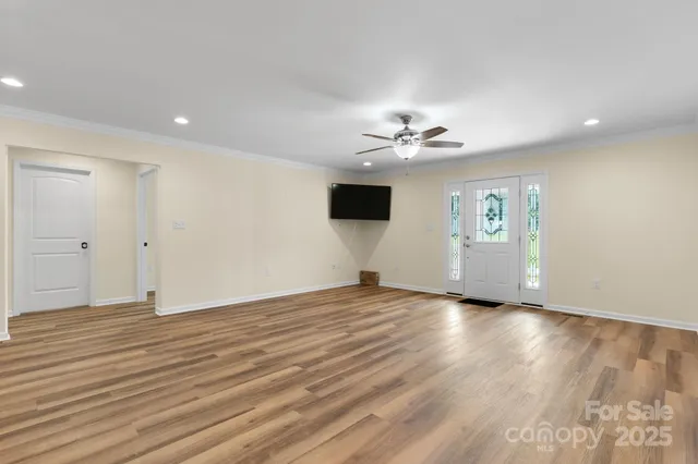 a view of an empty room with a window and wooden floor
