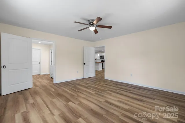 a view of empty room with wooden floor and ceiling fan