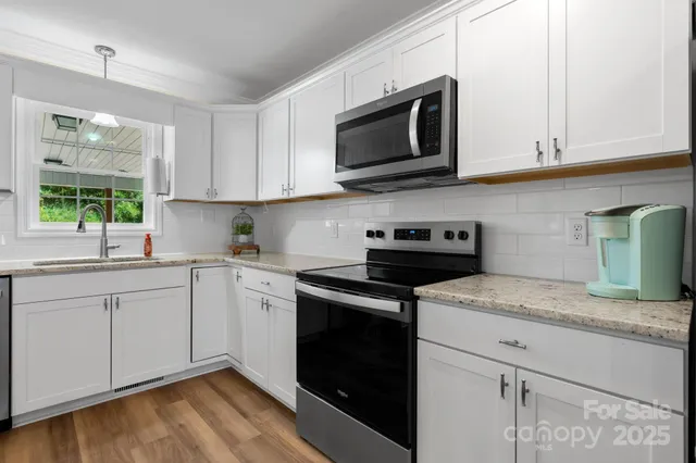 a kitchen with granite countertop white cabinets stainless steel appliances and a window